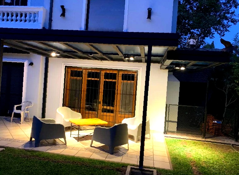 Pérgola con techo de vidrio iluminada de noche